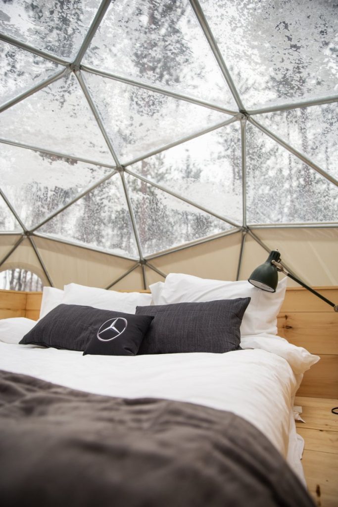 Inside geodesic glamping dome with Mercedes Benz branded pillow on bed