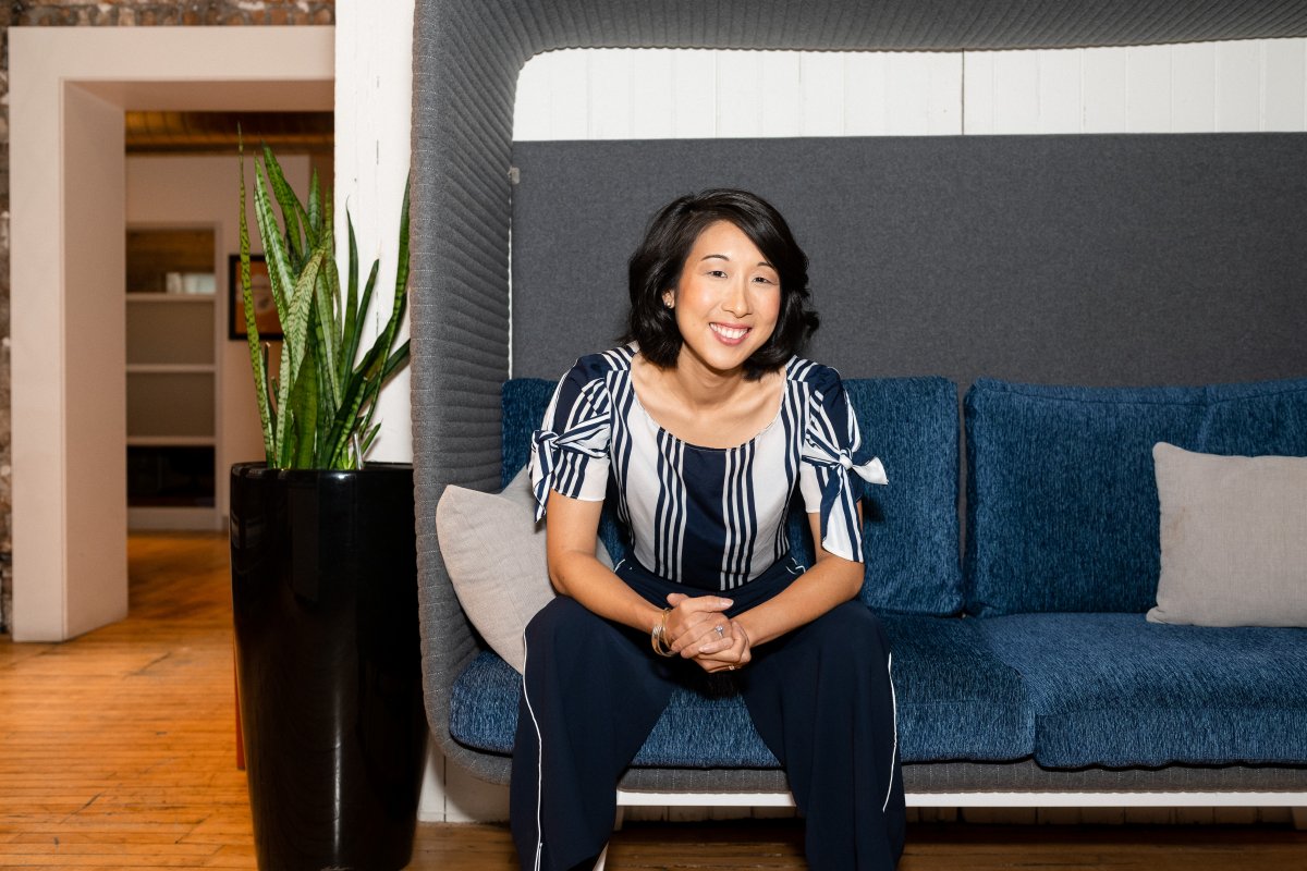 Jeanne Lam of Wattpad sits on a blue couch posing for a headshot.
