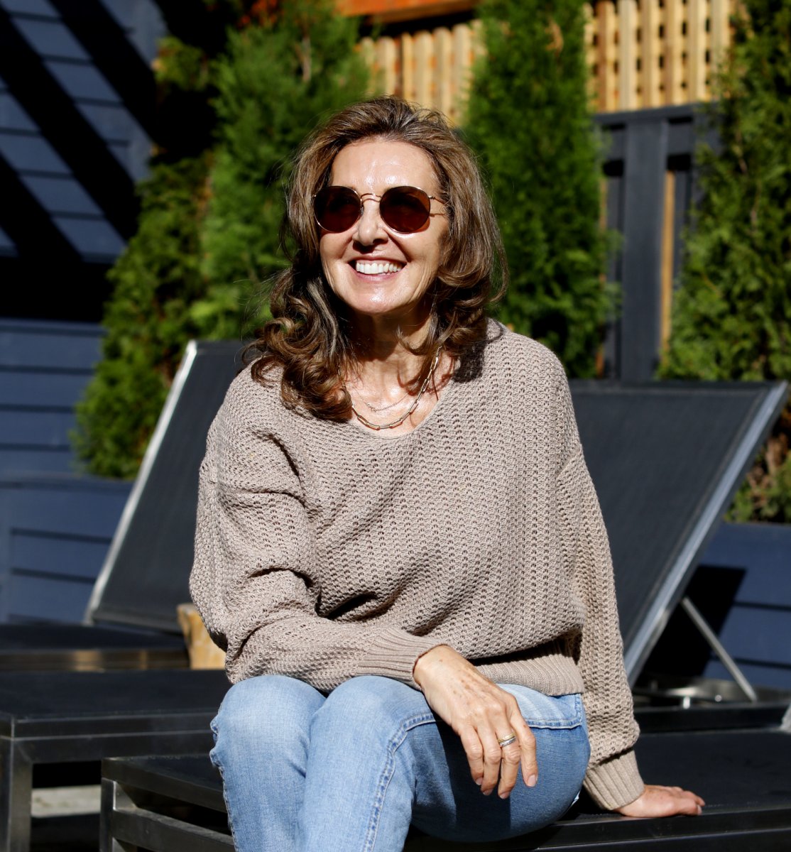 Pivot Skincare founder Cindy Berg sits on a lawn chair and smiles in the sun.