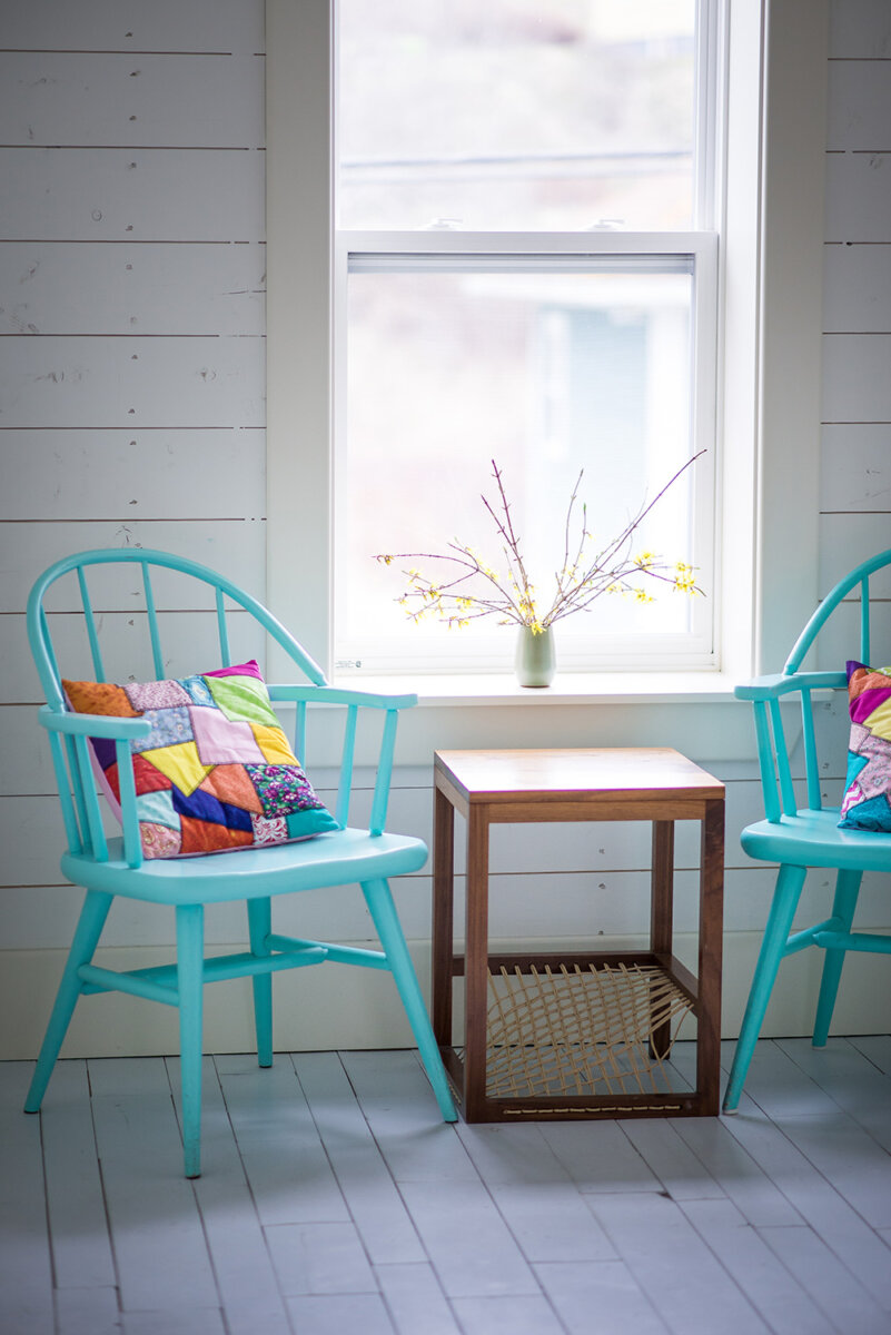 Motel room with blue chairs and quilted pillow