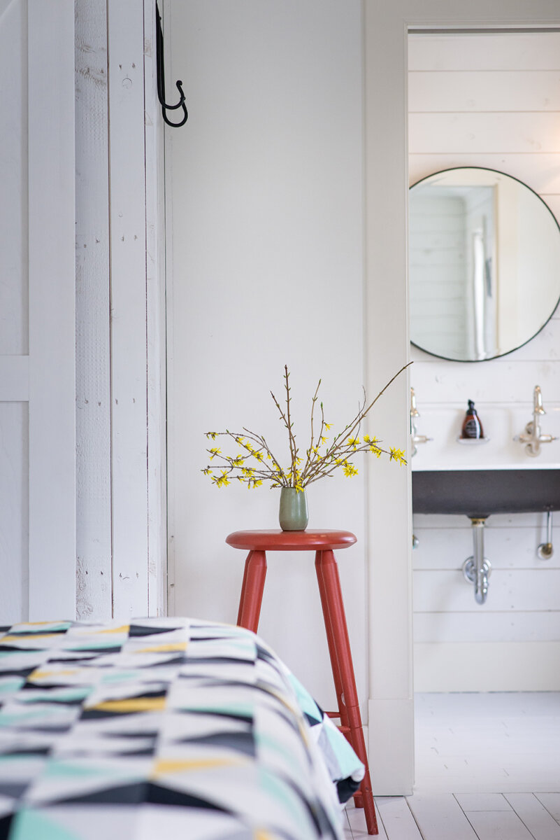 Motel room with quilted blanket and red stool with flowers