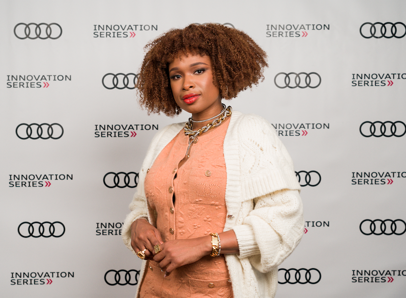Jennifer Hudson in white cardigan and peach blouse against Audi Innovation Backdrop