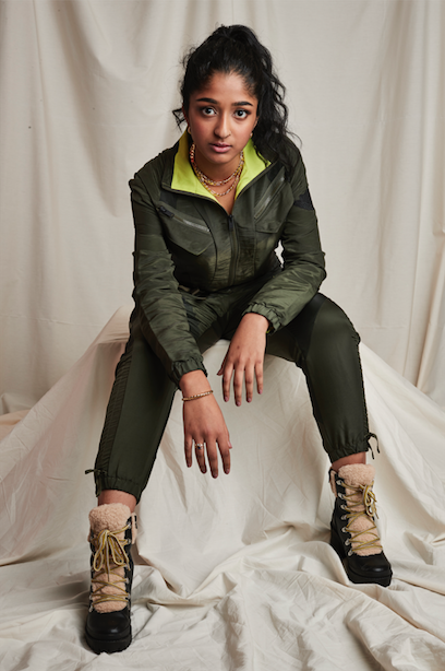 actor Maitreyi Ramakrishnan wearing green jacket sitting on stool draped in white cloth