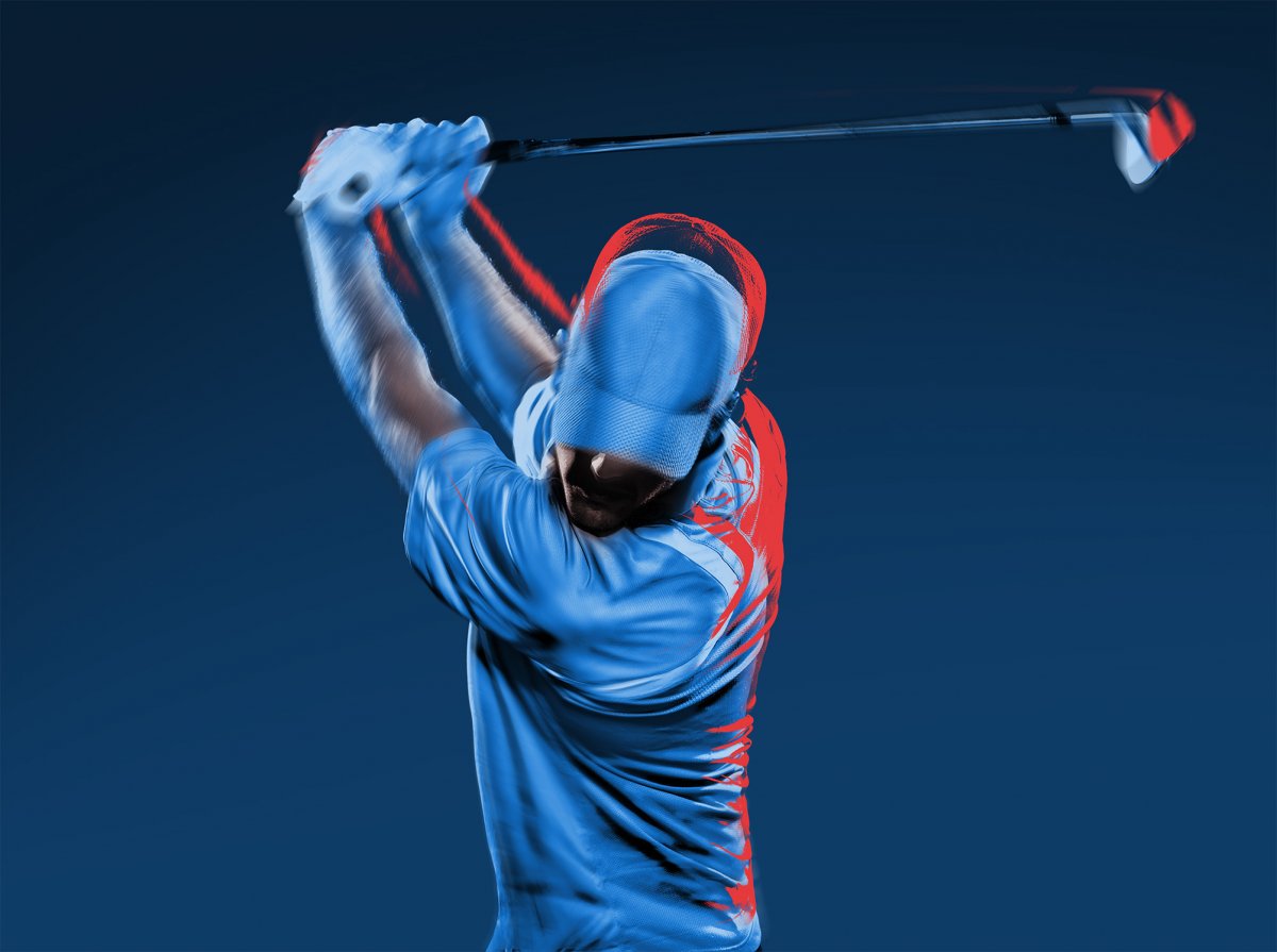 Golfer prepares to drive golf ball at the height of his swing.