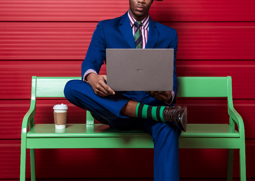 Man in blue suit sitting on bench with laptop