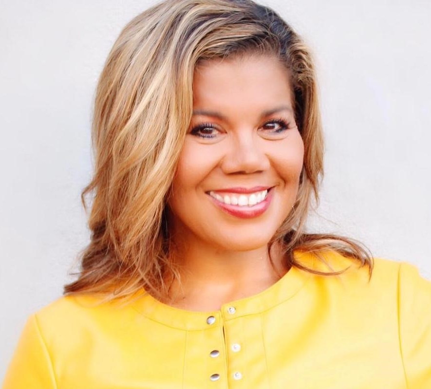 Suzanne Duncan, wearing a yellow shirt, smiles at the camera.