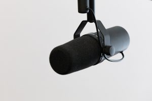 A black microphone suspended from a holster against a white background.