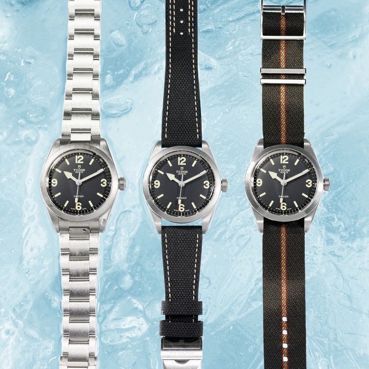 Three TUDOR Ranger watches set on blue ice. One has a steel bracelet, the middle watch has a black strap, and the right watch has a khaki green strap. All of them have black faces.