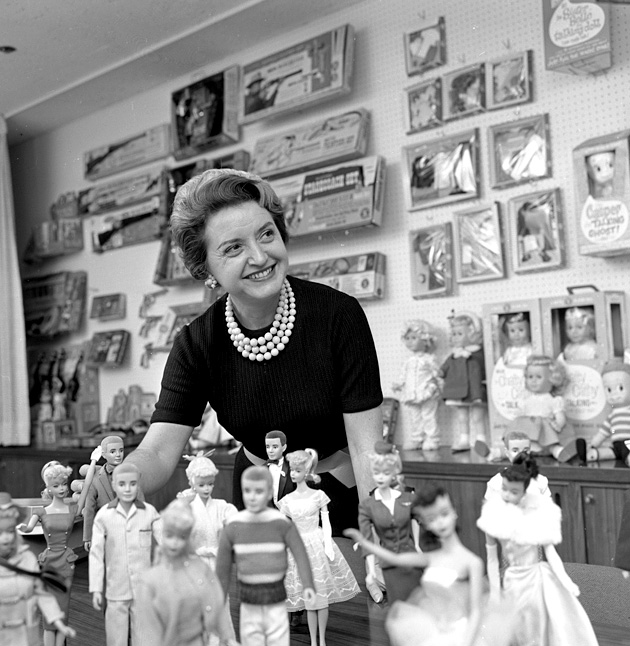 Black and white photo of Barbie and Mattel founder Ruth Handler in front of a group of dolls