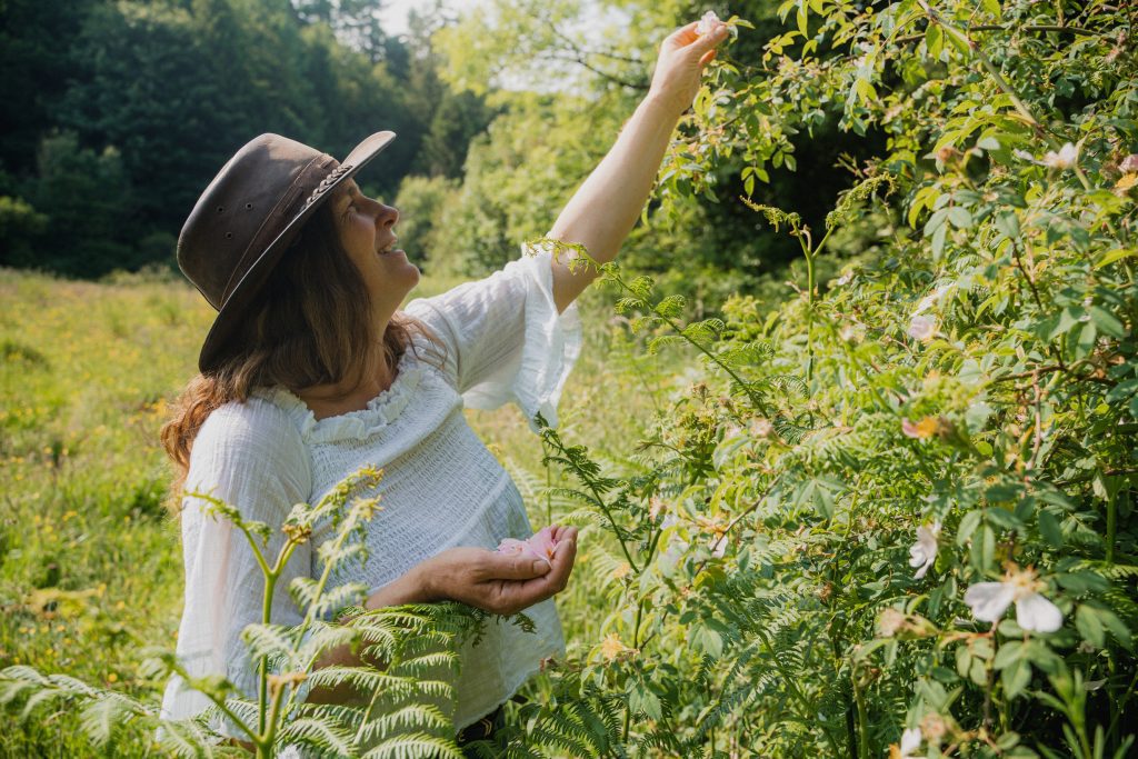 Geraldine Kavanagh in a field wearing a white blouse and brown leather hat foraging
