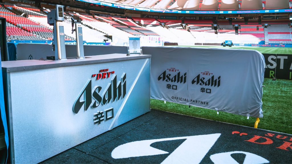 White satellite bars with Asahi beer branding looking out onto a green soccer field.