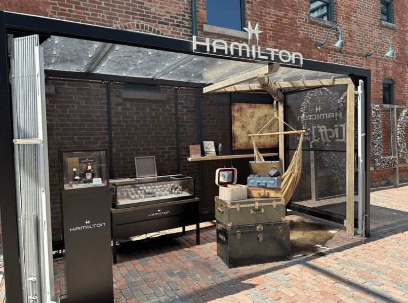 Hamilton watch booth outdoors. There are a bunch of displays and watch jewelery cases with some props to promote Indiana Jones.
