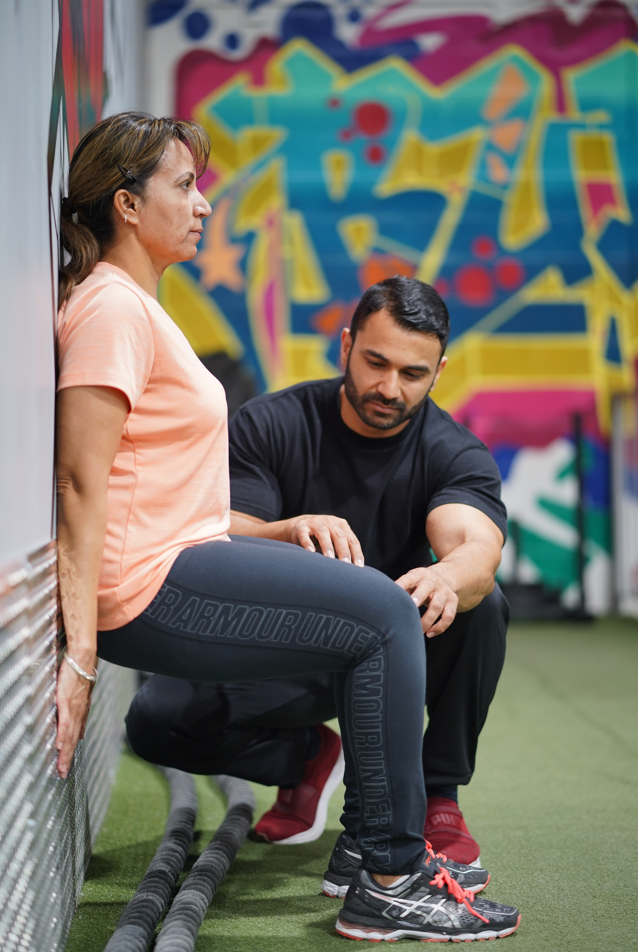 Photo of Sunny from My Bollywood Body helping a client during her workout.