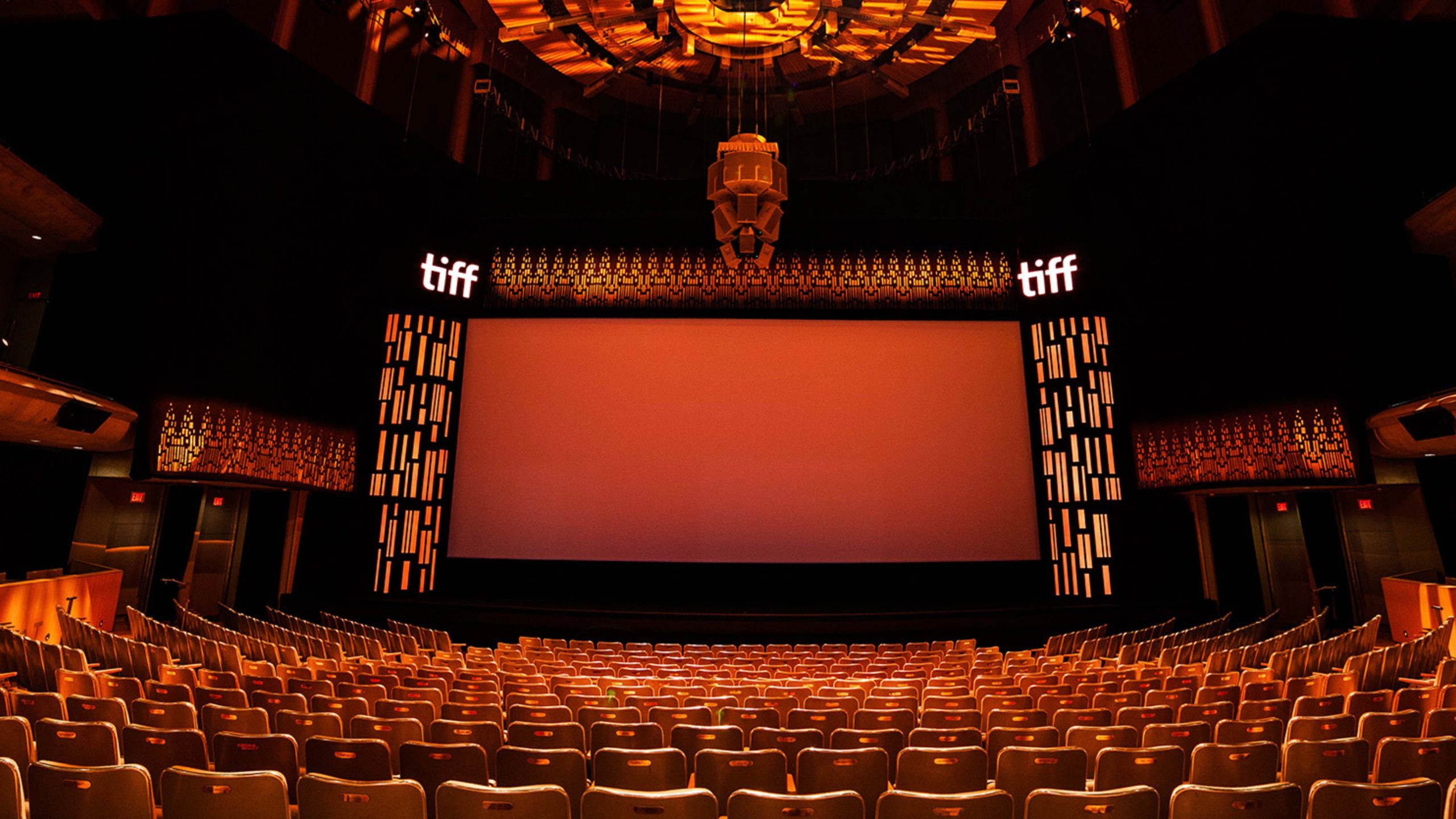 Auditorium of seats and speakers showing a glowing orange stage and TIFF branding.