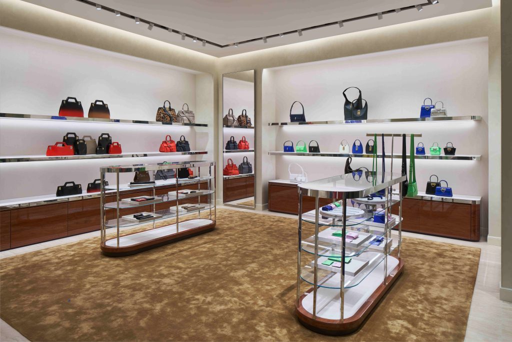 Photo of the inside of the new Ferragamo store. There are multiple bags on display in many colors like red, black, blue, green, and silver.