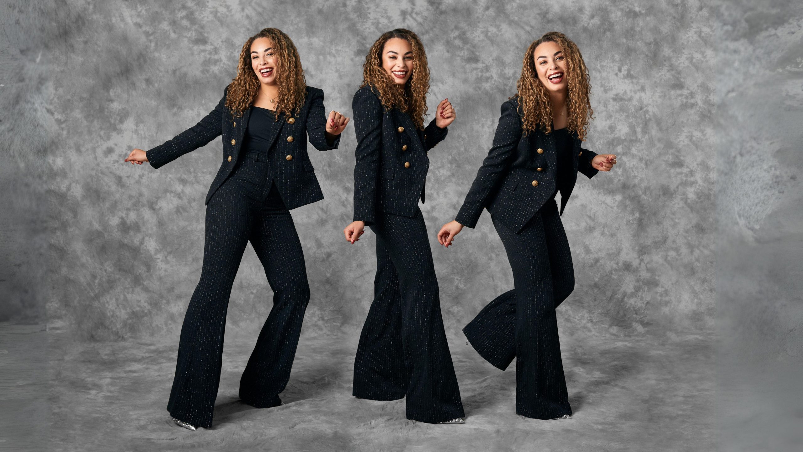 three versions of Sarah Nurse wearing a black suit dancing against a grey backdrop