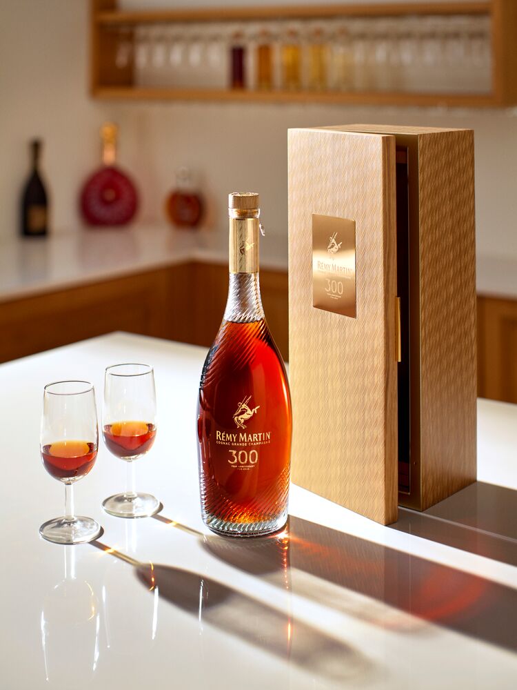 Bottle of Rémy Martin sitting on a countertop with two glasses and a box.