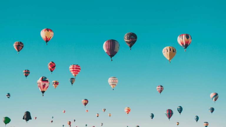 Blue skyscape filled with multicoloured hot air balloons.