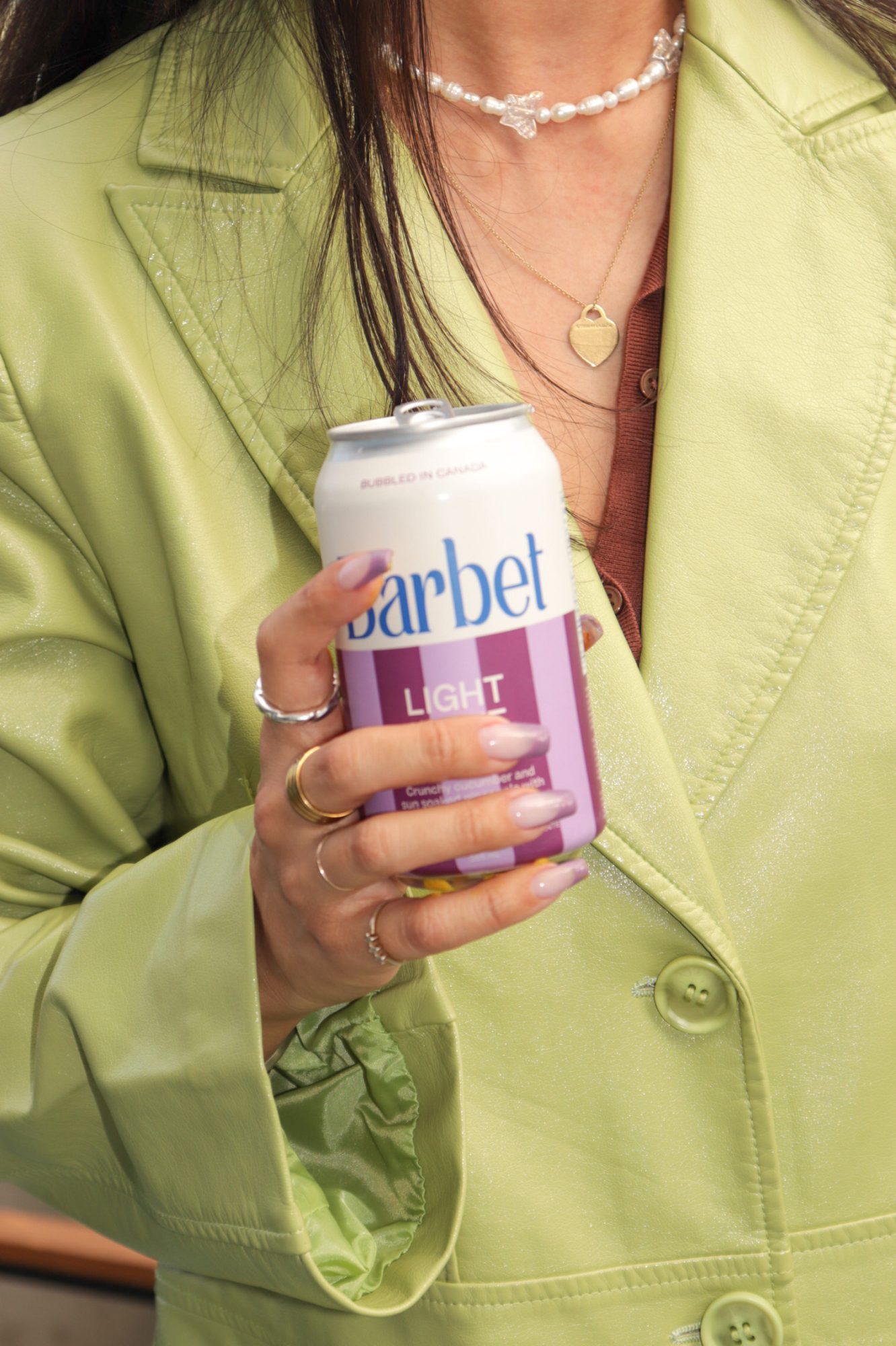 Woman in a lime green blazer holding a can of Barbet.